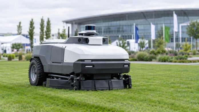 AI-generated illustration of a large commercial robotic mower on a park lawn beside a trade-show demonstration area (not a photo of the PUDU GT Series)